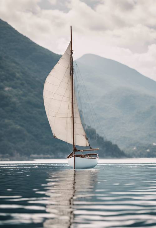 Um pequeno bote com velas brancas em um grande corpo de água com montanhas ao fundo.