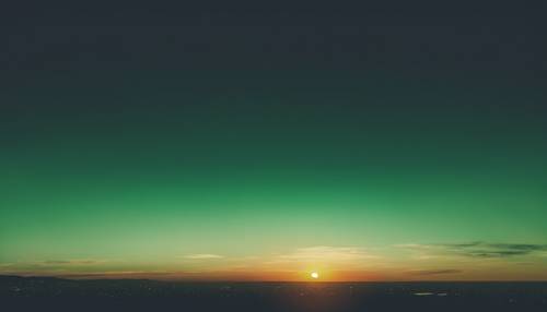 Un tramonto spettacolare dalle sfumature verdi con un orizzonte color smeraldo scuro che sfuma in un cielo verde mela chiaro.