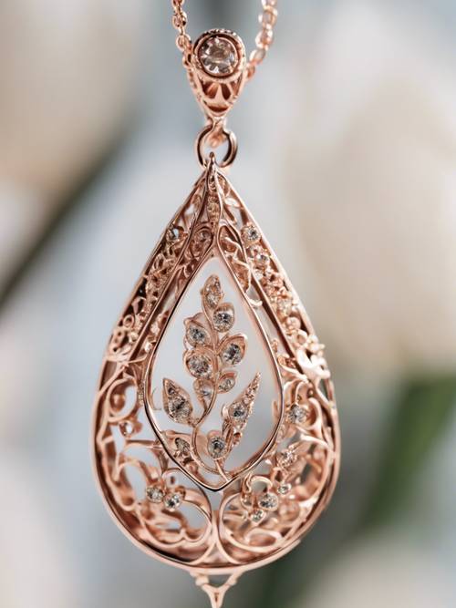 A close-up of a rose gold teardrop-shaped pendant with an intricate, floral design.