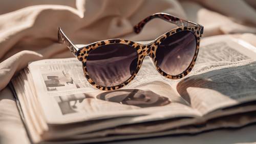 Parlak bir derginin üzerinde duran bir çift şık çita desenli güneş gözlüğü.
