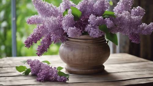 Rustic vase on a wooden table filled with a bunch of fresh lilacs.
