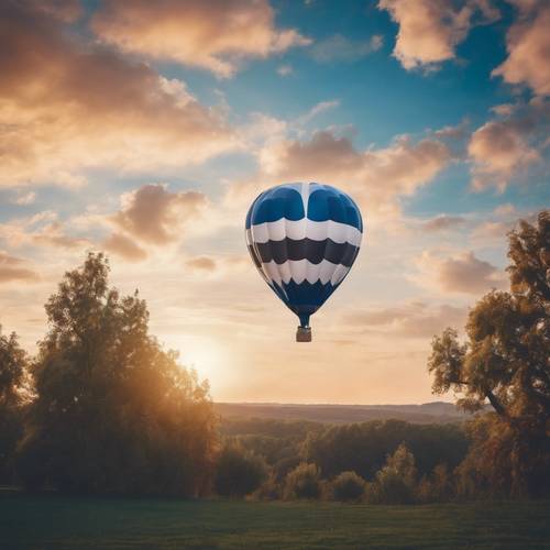 Balon na ogrzane powietrze w niebiesko-białe paski spokojnie unoszący się na kolorowym wieczornym niebie.