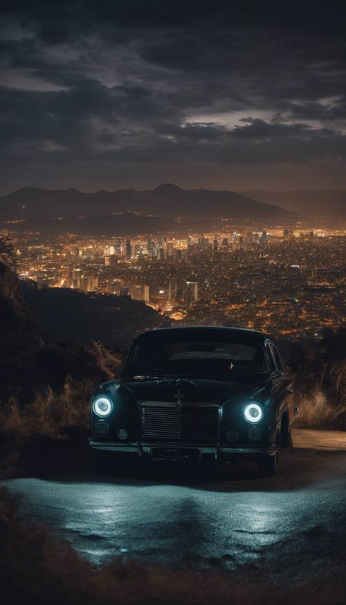 Dark car parked near a cliff with the nighttime skyline in the distance.