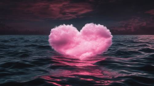 Różowa chmura w kształcie serca unosząca się nad czarnym nocnym morzem.