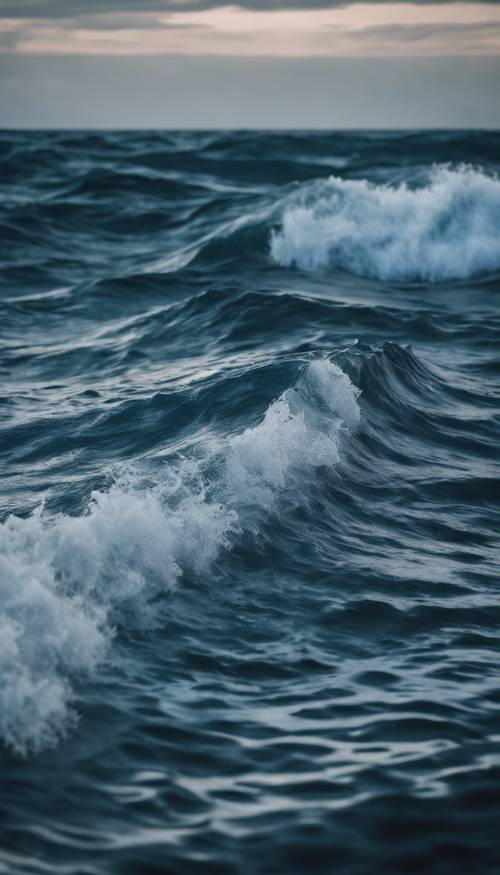 موجات زرقاء داكنة تشكل نمطًا منتظمًا بشكل إيقاعي على محيط هادئ.