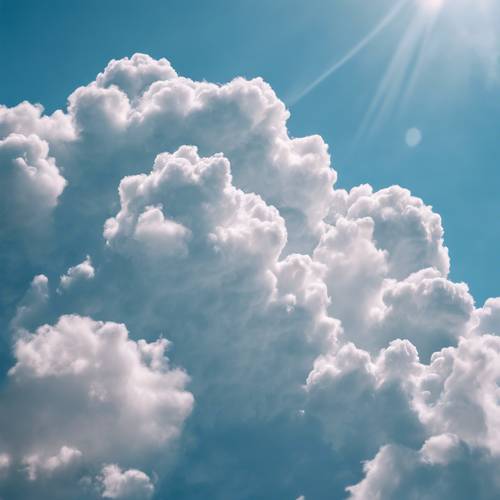 Soft, fluffy clouds floating across a clear blue sky on a warm, sunny day.