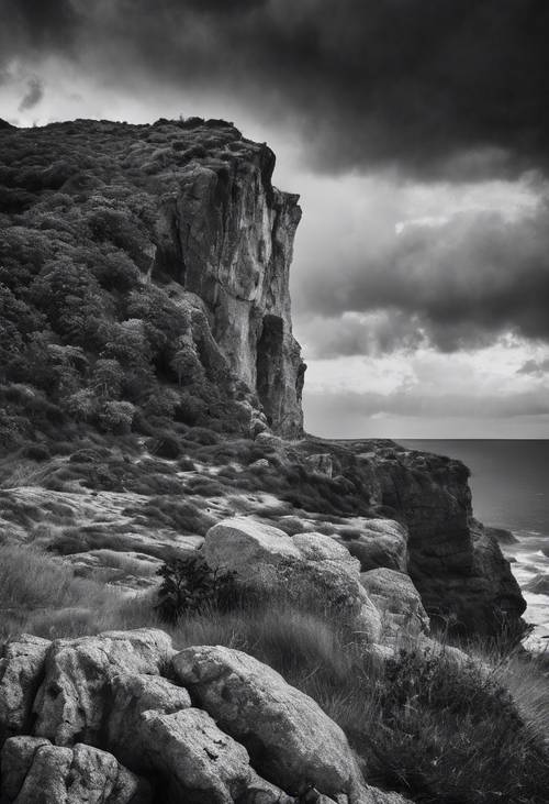 Black and white image of a dramatic cliffscape under a stormy sky.