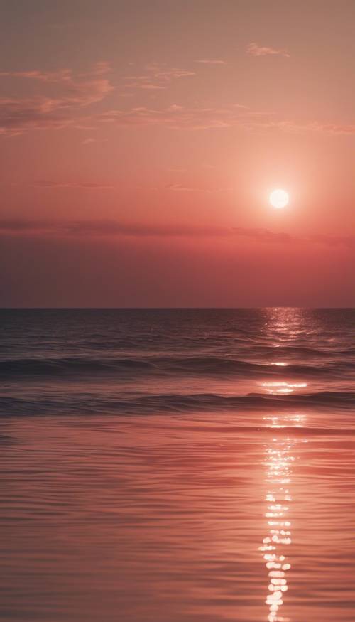 A serene sunset casting a light red glow over a calm sea.
