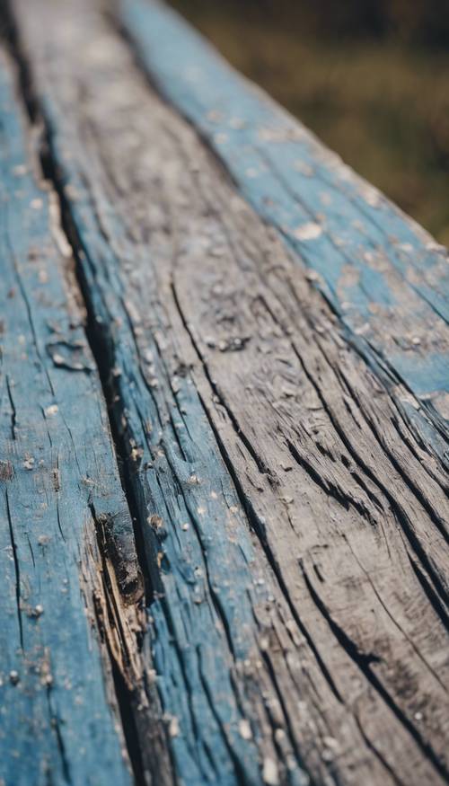 Tampilan jarak dekat dari sepotong kayu bercat biru pudar, lapuk oleh waktu.