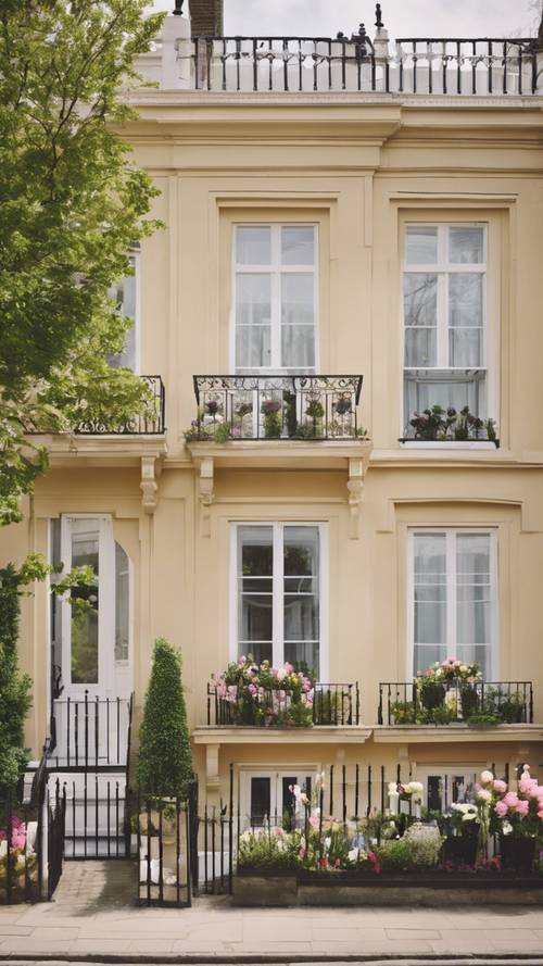 Una casa a schiera in stile georgiano con una maestosa facciata color crema, una fila di finestre a ghigliottina e una vivace esposizione di fiori primaverili all&#39;ingresso.