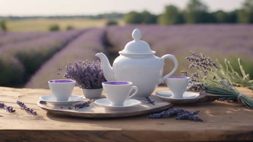 A traditional light gray tea set served on a rustic wooden table with a field of lavender in the background.