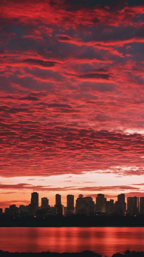 Eine lebendige Szene eines Sonnenuntergangs, bei dem der Himmel von roten Streifen durchzogen ist und ins Schwarz übergeht.