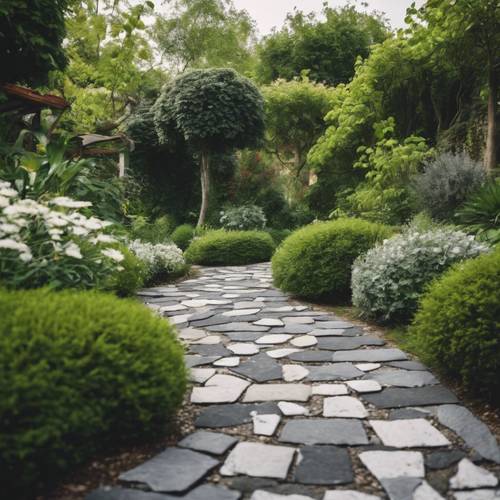 A flagstone path made of mixed grey, white, and black stones in a lush green garden.