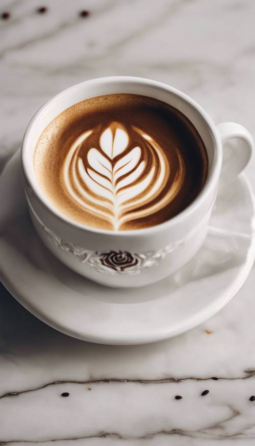 Una tazza di caffè con un preciso motivo a rosetta di latte art posizionata su un ripiano in marmo.