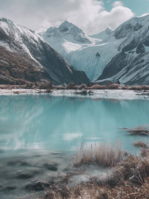 A scenic view featuring a pastel blue glacial lake nestled in snow-capped mountains.