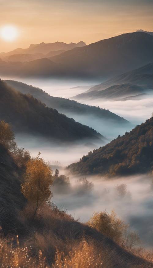 A mountain landscape during golden light of dawn, with mist in the valley.