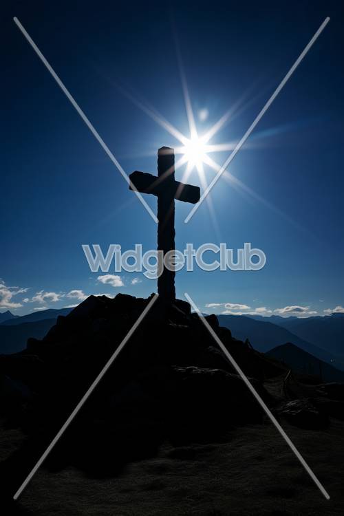 Luz do sol brilhando atrás da cruz no cume da montanha