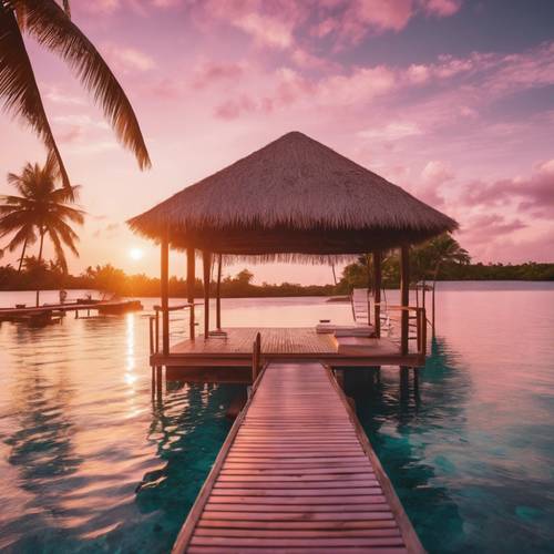 Un bungalow sur pilotis face à un coucher de soleil éclairé en rose sur un lagon tropical tranquille.