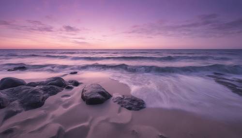 Uma vista panorâmica de um mar calmo sob um céu roxo pastel ao entardecer.