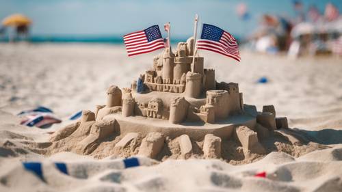 Sahilde Amerikan bayraklarıyla süslenmiş bir kumdan kale ve 4 Temmuz&#39;u simgeleyen parlak mavi bir gökyüzü.