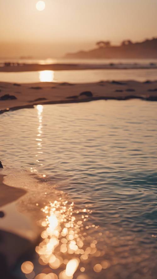 Luksusowy basen bez krawędzi przy plaży z widokiem na spokojne morze o zachodzie słońca.