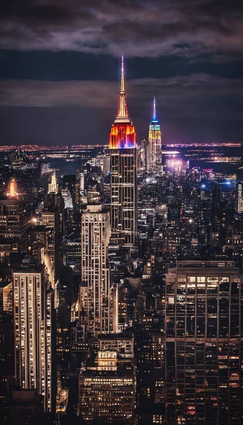 Renkli ışıklarla aydınlatılan, karanlık New York gökyüzünü delen ikonik Empire State Binası.