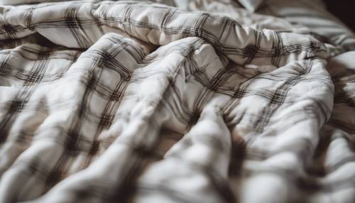 Un paio di comodi pigiami di flanella scozzese bianca su un morbido letto con un soffice piumino.