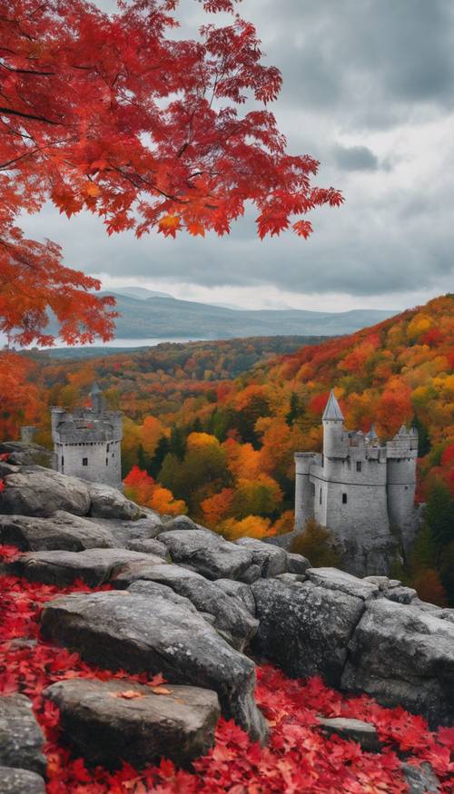 A scenic landscape during fall where red maple leaves mix with the gray stone of a castle.