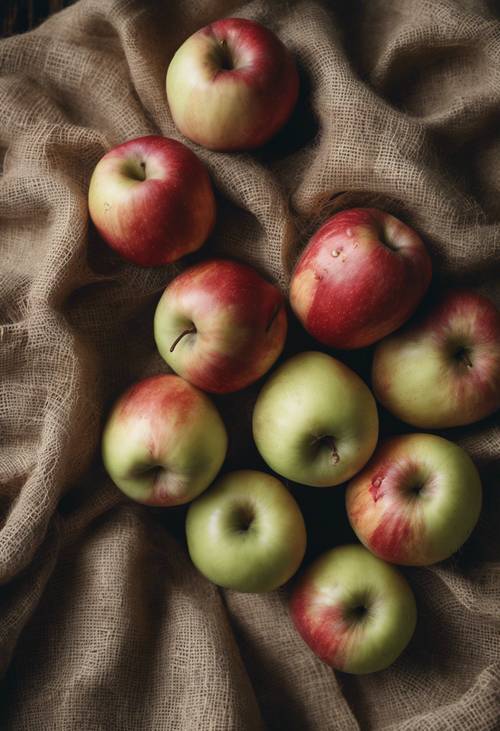 Uma natureza morta rústica de um grupo de maçãs dispostas sobre um pano de juta