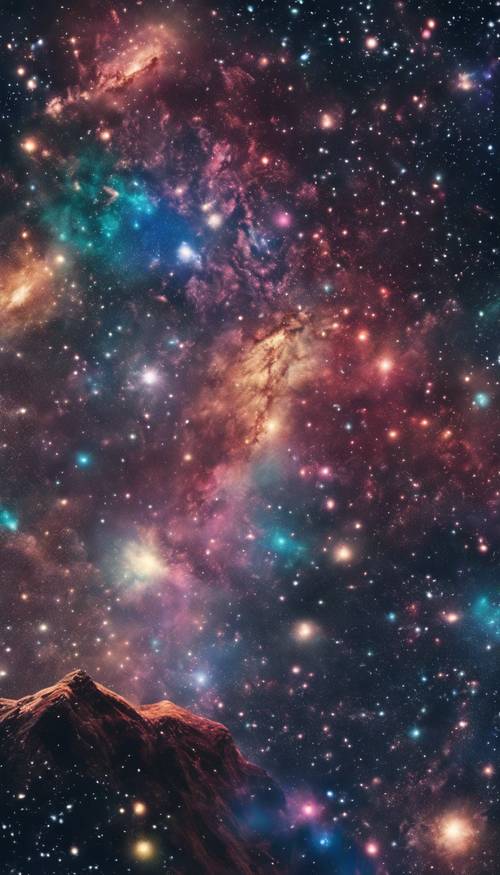 Un cielo pieno di galassie e costellazioni colorate visto da un&#39;alta vetta montuosa.