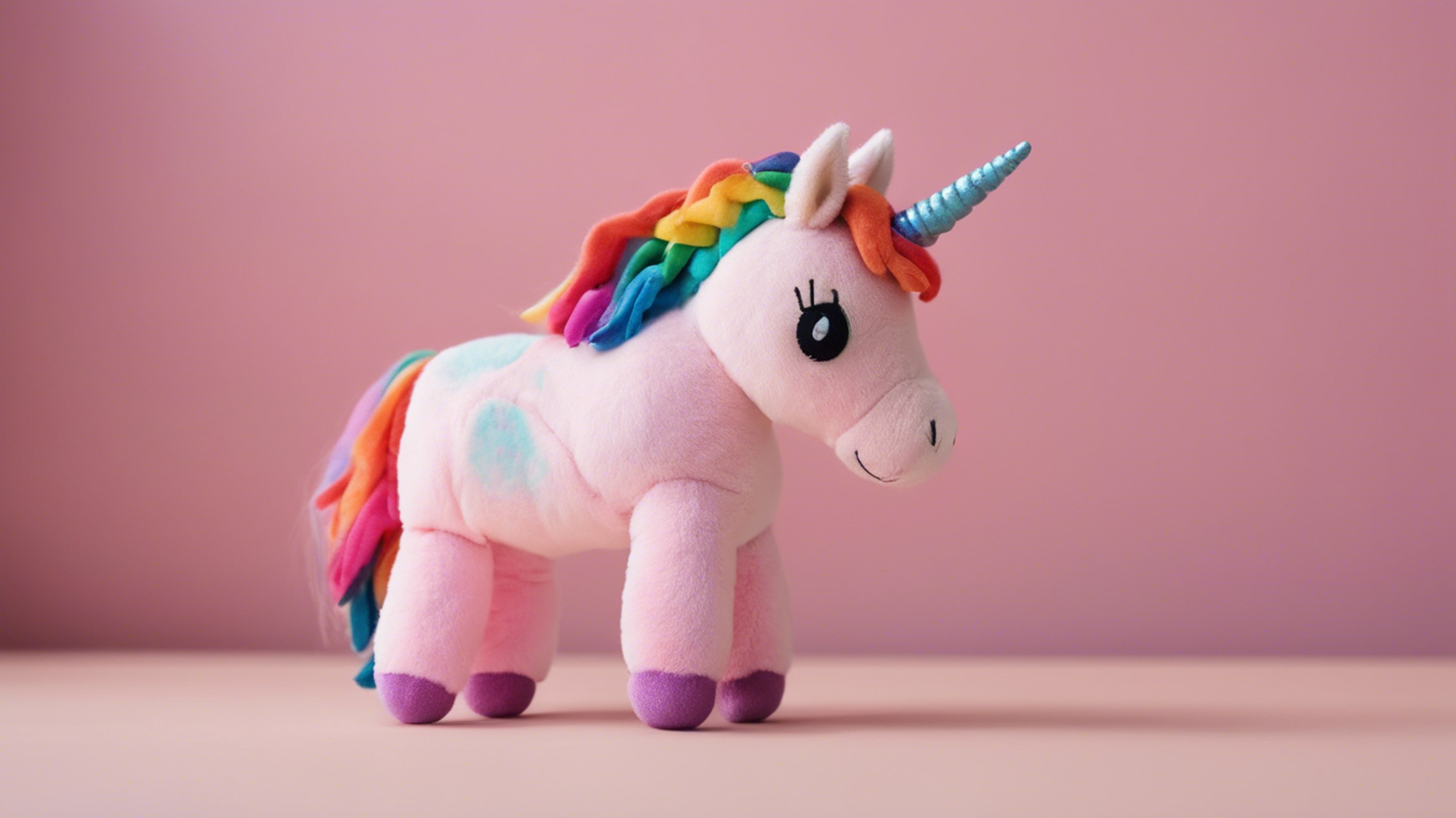 A rainbow-colored unicorn plushie in front of a pastel pink wall.壁紙[b4b7619b69e941578866]
