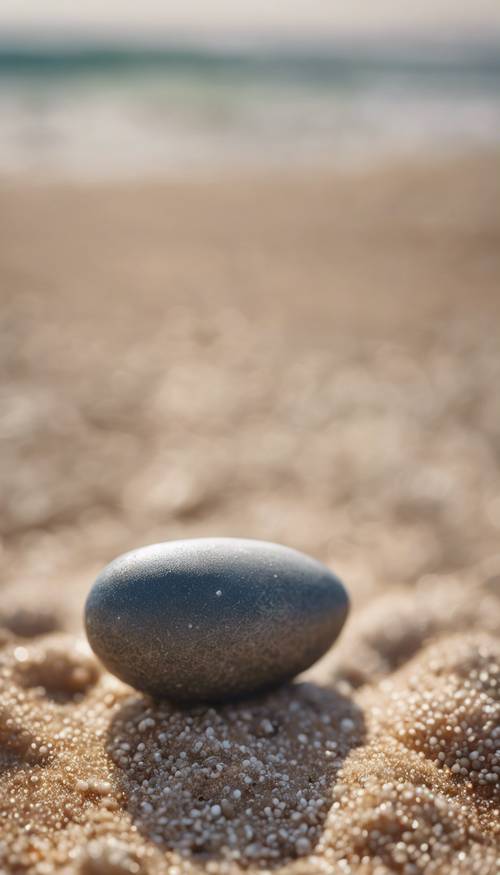 A single pebble resting on a sandy beach.