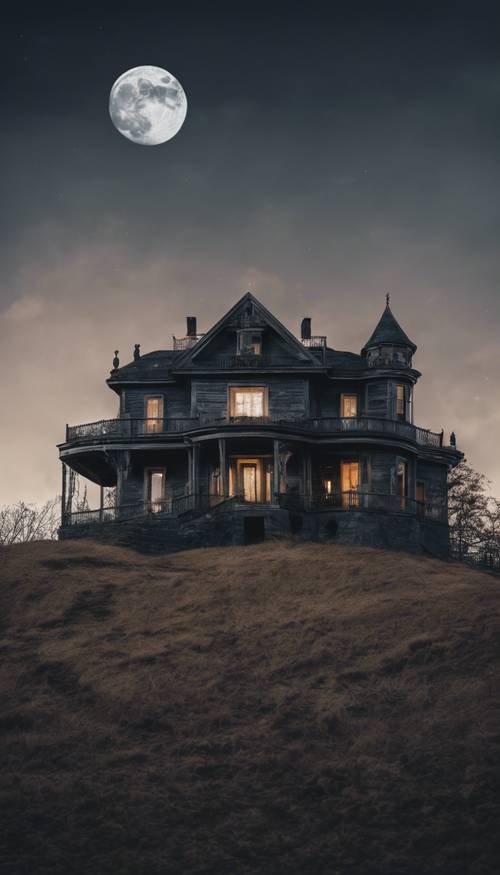 Widok nawiedzonego domu na wzgórzu z pełnią księżyca w tle.