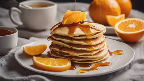 An appetizing dish of fluffy pancakes topped with fresh slices of juicy orange and a drizzle of syrup. Tapet [54505d9a75de4881a127]