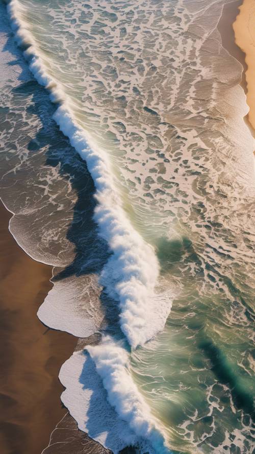 An aerial beach view, capturing the intricate pattern of crashing waves on the shoreline.