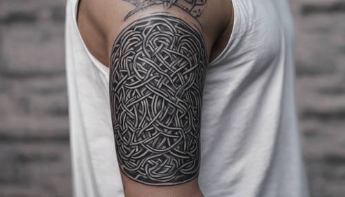 Celtic knotwork tattoo forming a band around the bicep in black and grey.