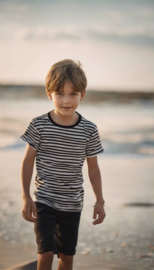 A young boy wearing a black striped t-shirt, playing on the beach.