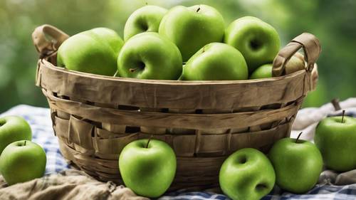 Una collezione di mele verdi lucide appena raccolte, poste in un cestino di legno rustico posto su un panno a quadretti.
