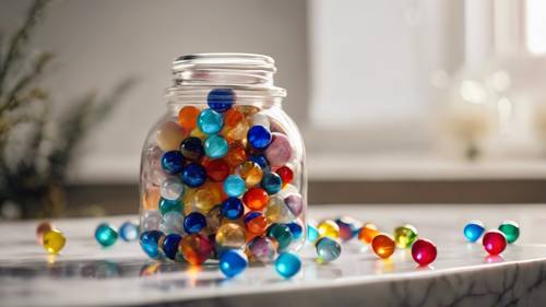 A glass jar full of colorful marbles with glinting lights around them, placed on a white marble surface.