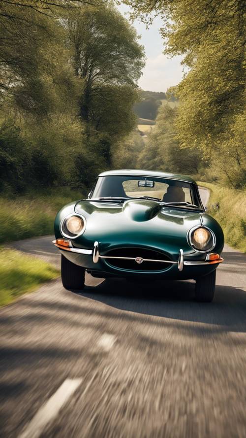 Jaguar E-Type klasik Inggris melaju di jalan pedesaan yang indah, pepohonan melintas.