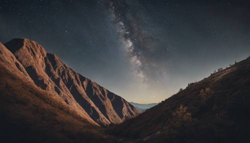Một ngọn núi gồ ghề và dốc được chụp dưới bầu trời đêm đầy sao.