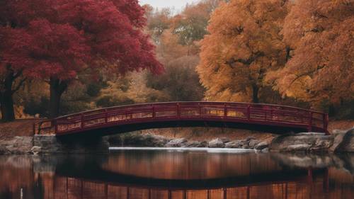 A cool maroon bridge stretching across a serene body of water during autumn.