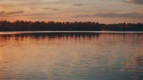 Uma imagem de um lago calmo ao pôr do sol, com ondulações na água sutilmente formando uma citação de anime.