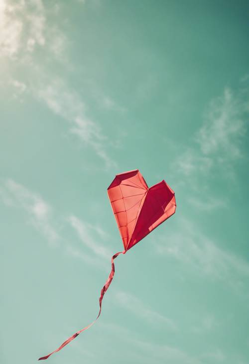 A flying heart-shaped kite brushed with sage green color against the backdrop of a bright, summer sky.
