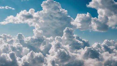 Açık mavi gökyüzünü kaplayan kümülüs bulutlarının panoramik görüntüsü.