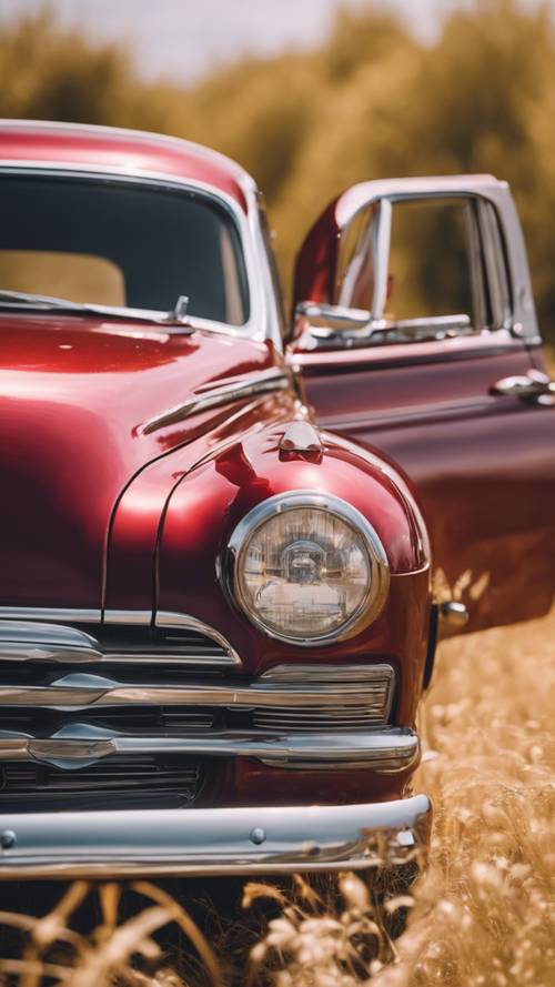 Altın rengi bir bozkırda park edilmiş, parlak bir şekilde parlatılmış kiraz kırmızısı eski model bir araba.