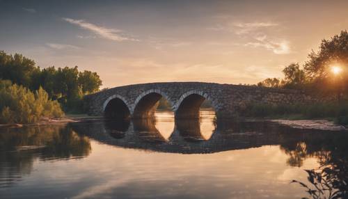 日落时分，一座石桥横跨平静的河流。