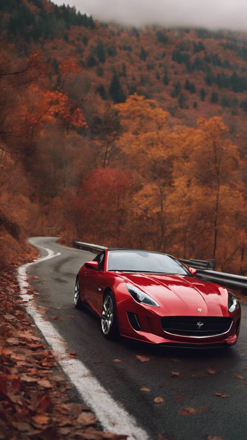 Une voiture de sport rouge brillant qui court sur une route de montagne en automne.