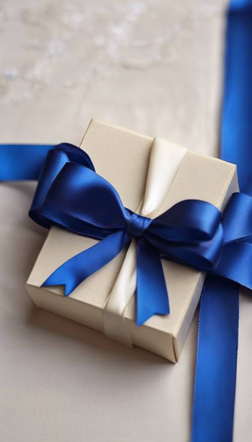 Zu filigranen Schleifen gebundene königsblaue Satinbänder verzieren eine wunderschön verpackte elfenbeinfarbene Geschenkbox.