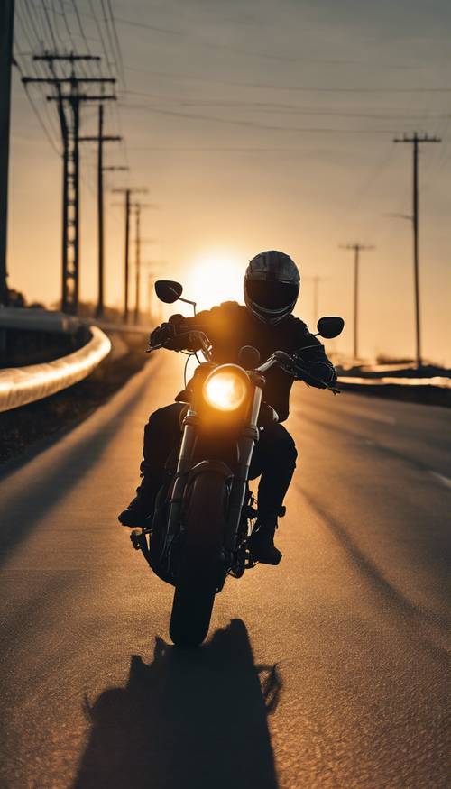 The silhouette of a motorcyclist driving towards the sunrise on a highway. Tapet [3401bbcc85bf4e4a8b94]
